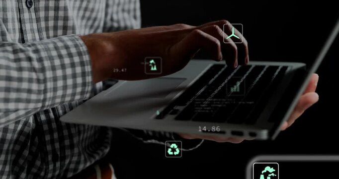 Male holding laptop lefthand, typing righthand in studio, causing eco overlays shifting: chart, CO2