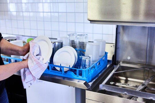 Mann trocknet einen Teller mit einem Geschirrtuch ab in einer Grossk&uuml;che