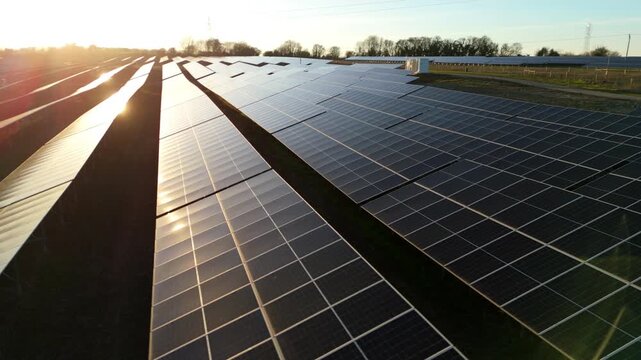 Aerial view of Tye Lane Solar farm, with rows of panels reflecting the sunlight, creating a shimmering contrast against the dark ground, Ipswich, United Kingdom.