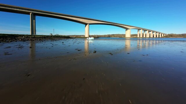 Aerial FPV view of a stranded boat sitting under a large concrete bridge as the tide goes out, Ipswich, England, United Kingdom.