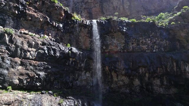 Beautiful aerial view of a stream of water flowing down a high, rugged cliff after recent heavy rains in Gran Canaria, Canary Islands