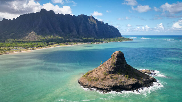 Aerial view of the iconic, cone-shaped islet of Mokolii rising from the turquoise waters against the backdrop of the majestic Ko'olau mountain range, Kaneohe, Hawaii, United States.