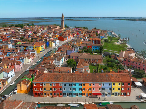 Aerial view of vibrant houses explode in a riot of colors along the canals, crowned by the distant San Martino bell tower, Burano, Veneto, Italy.