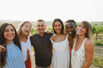 Fototapeta premium Happy multiracial friends having fun outdoor with vineyards in background - Travel, friendship and summer holidays concept - Main focus on center people faces