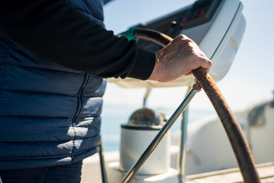 Person hand steering boat helm during sailing trip