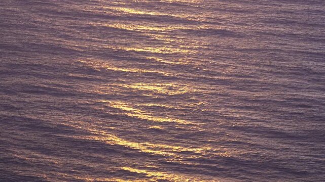 Ocean sunset waves rippling abstract water texture during golden hour, reflecting beautiful light on the surface.