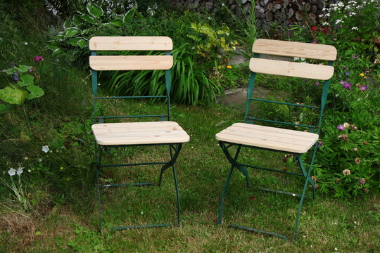 Zwei Rustikale Gartenst&uuml;hle im Garten vor Blumenbeet