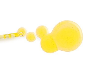 Pipette with drops of yellow cosmetic oil on white background