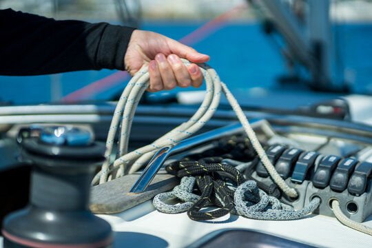 Hand working with rope and winch on sailboat deck