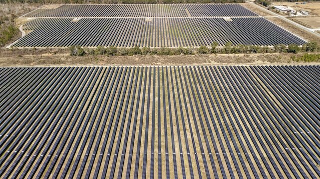 Aerial view of vast solar panel arrays stretching across the landscape, reflecting the sky above, Elkton, Florida, United States.