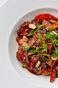 Gourmet saut&eacute;ed vegetables garnished with fresh mixed greens and sesame seeds, served on a white plate. Healthy vegetarian warm appetizer, top view.