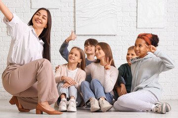 Fototapeta premium Female guide with children taking selfie at exhibition in art gallery