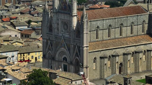 Panoramic drone shot Orvieto Cathedral Duomo Umbria. Gothic architecture marble building facade ancient town background summer. Authentic italian travel experience. Religious monument tourism footage.