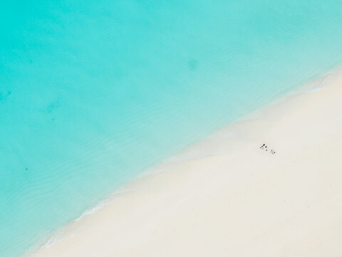 Aerial view of turquoise waters meeting the pristine white sands, a tranquil paradise unfolds beneath the drone's gaze, Vashafaru Island, Maldives.