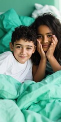 Obraz premium Young siblings smiling together on bed with green bedding