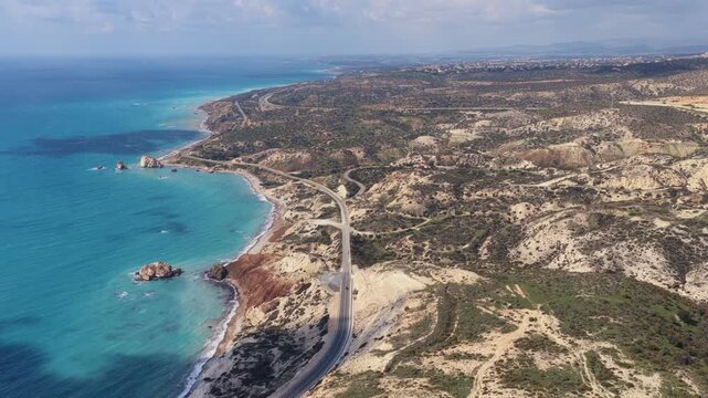 Aerial drone view of Cyprus coastline featuring rolling hills, coastal roads and turquoise Mediterranean waters
