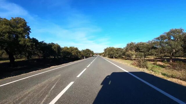 Open road lifestyle driving through empty countryside asphalt under bright summer sky, freedom living concept. POV from vehicle moving without limits toward destination surrounded by nature and wide l