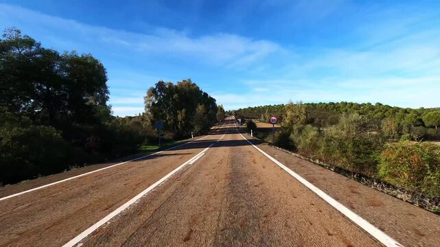 Driving perspective on empty rural asphalt road symbolizing direction and navigation, travel concept. POV from vehicle moving forward through countryside under blue sky, choosing path and reaching des