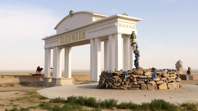 Sainshand, Mongolia - September 9, 2019: A sacred pile of stones (ovoo, obo) and
symbolic gate of Sainshand city against a backdrop of the blue scenic sky.
