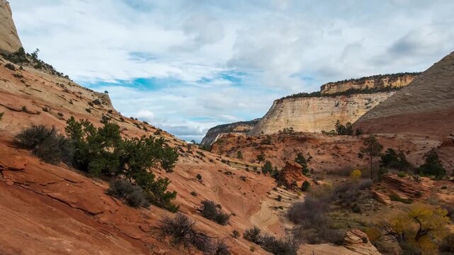 wide-angle shot of the iconic red rock formations and deep canyons of Zion National Park in Utah. The footage captures the dramatic contrast between the cream and orange Navajo sandstone cliffs, a bri
