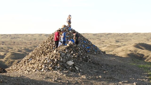 Mongolia, Sainshand - September 6, 2019: A sacred ritual structure in the form of a heap of stones (obo, ovoo) in the Gobi Desert, Mongolia. People make a ritual ovoo bypass. Summer sunny day.
