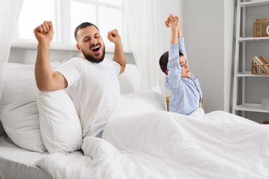Morning of happy father with his son in pajamas on bed at home