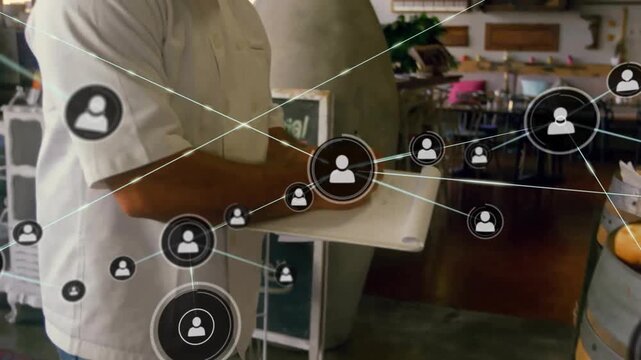 Animation of network of connections with icons over caucasian cook in kitchen