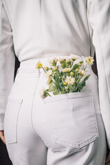 Nature meets fashion concept with white daisies in back pocket, minimalist style, natural beauty, organic detail in modern clothing, fresh spring aesthetic