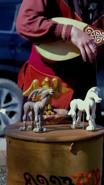 Kazakh street musician playing dombra with moving puppet toys, traditional culture performance