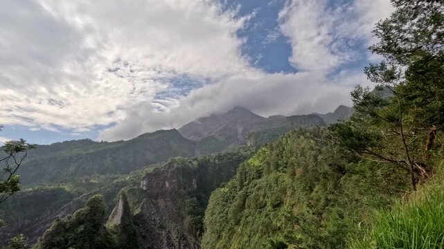 Timelapse of active Mount Merapi volcano with passing clouds, light and shadow play on slopes and swaying trees