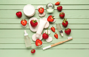Naklejka premium Different cosmetic products and strawberries on green wooden background