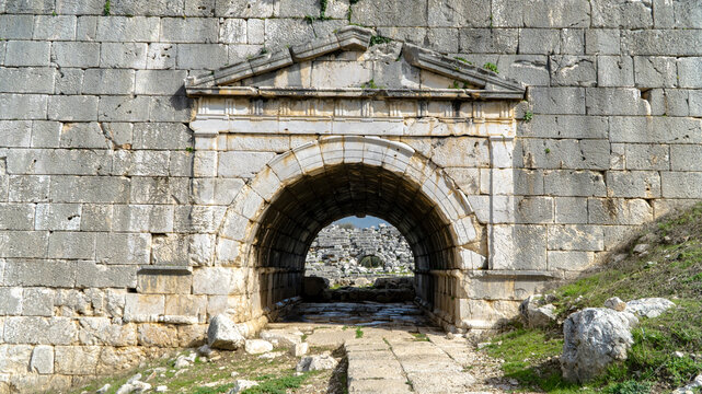 Ancient stone gateway at Letoon sanctuary, featuring arched entrance, weathered walls and pathway leading into historic Lycian ruins, historic Lycian ruins near city of Xanthos, Mugla, Turkey