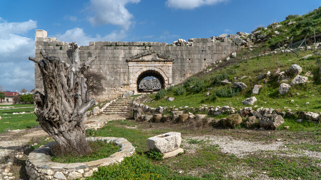 Ancient stone gateway at Letoon sanctuary, featuring arched entrance, weathered walls and pathway leading into historic Lycian ruins near city of Xanthos