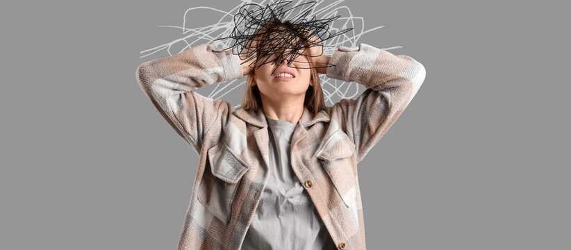 Portrait of worried young woman on grey background