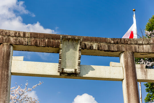 Detail view of weathered stone torii gate and Japanese national flag outdoors