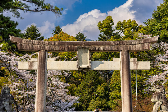 Historic stone torii gate standing against blue sky and white clouds in Japan