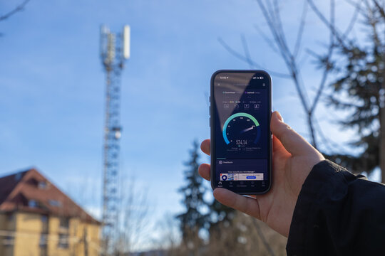 Szklarska Poreba, Poland - December 16, 2025: Speedtest application displaying high 5G mobile internet download speed on a smartphone near a cell tower