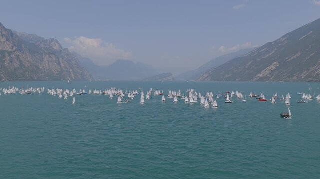 Stunning 4K drone footage of a sailing regatta captured in a smooth transition from a horizontal perspective to a top-down view. Multiple sailboats glide across vibrant turquoise water