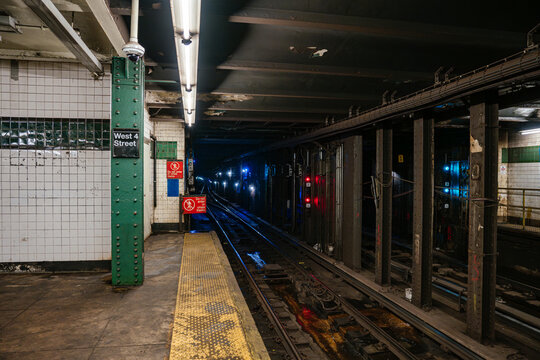 New York City, New York, USA - 08.03.2024: Dark underground New York City subway tunnel with red signal lights and railway tracks at West 4 Street station. Industrial metro infrastructure with warning
