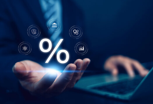 Business finance concept with glowing percentage symbol above businessman hand using laptop, representing interest rate, investment, banking, financial growth, digital economy.