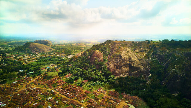 Aerial view of the rugged, rocky landscape contrasting with the clustered buildings below, all under a sky of scattered clouds, Ibadan, Nigeria.