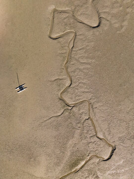 Aerial view of a small boat sailing in Abel Tasman National Park with winding streams of water, Abel Tasman, Tasman Region, New Zealand.