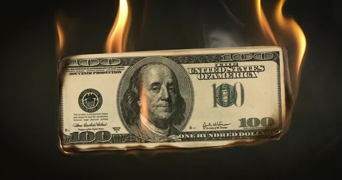 Burning dollar bill with flames on dark background.