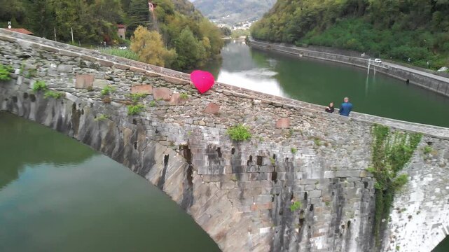 Aerial overhead view of Devils Bridge, Lucca. Red heart shape umbrella on the bridge