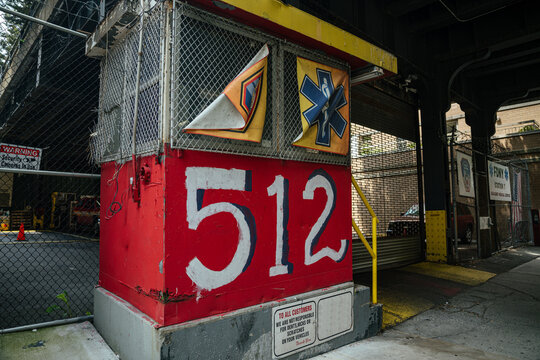 New York City, New York, USA - 08.02.2024: A red FDNY 512 fire station structure is shown beneath an elevated rail line in Manhattan. Safety signage and emergency symbols highlight public protection