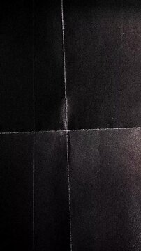 Vertical black crumpled paper background with light flashes.