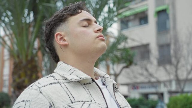 Man tilting head back showing neck tattoo and closed eyes on a street lined with buildings; calm introspection.