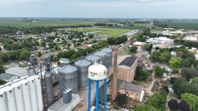 Aerial view of towering grain elevators casting shadows on the landscape, with a water tower punctuating the skyline, Grenora, United States.