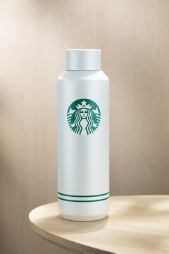 Minimalist insulated bottle with Starbucks logo placed on a wooden table, clean background, modern lifestyle concept, reusable drinkware and eco-friendly trend.