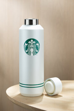 Minimalist insulated bottle with Starbucks logo placed on a wooden table, clean background, modern lifestyle concept, reusable drinkware and eco-friendly trend.